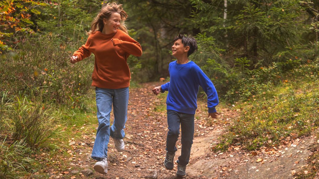 Två syskon leker och springer genom naturreservatet Gömmaren